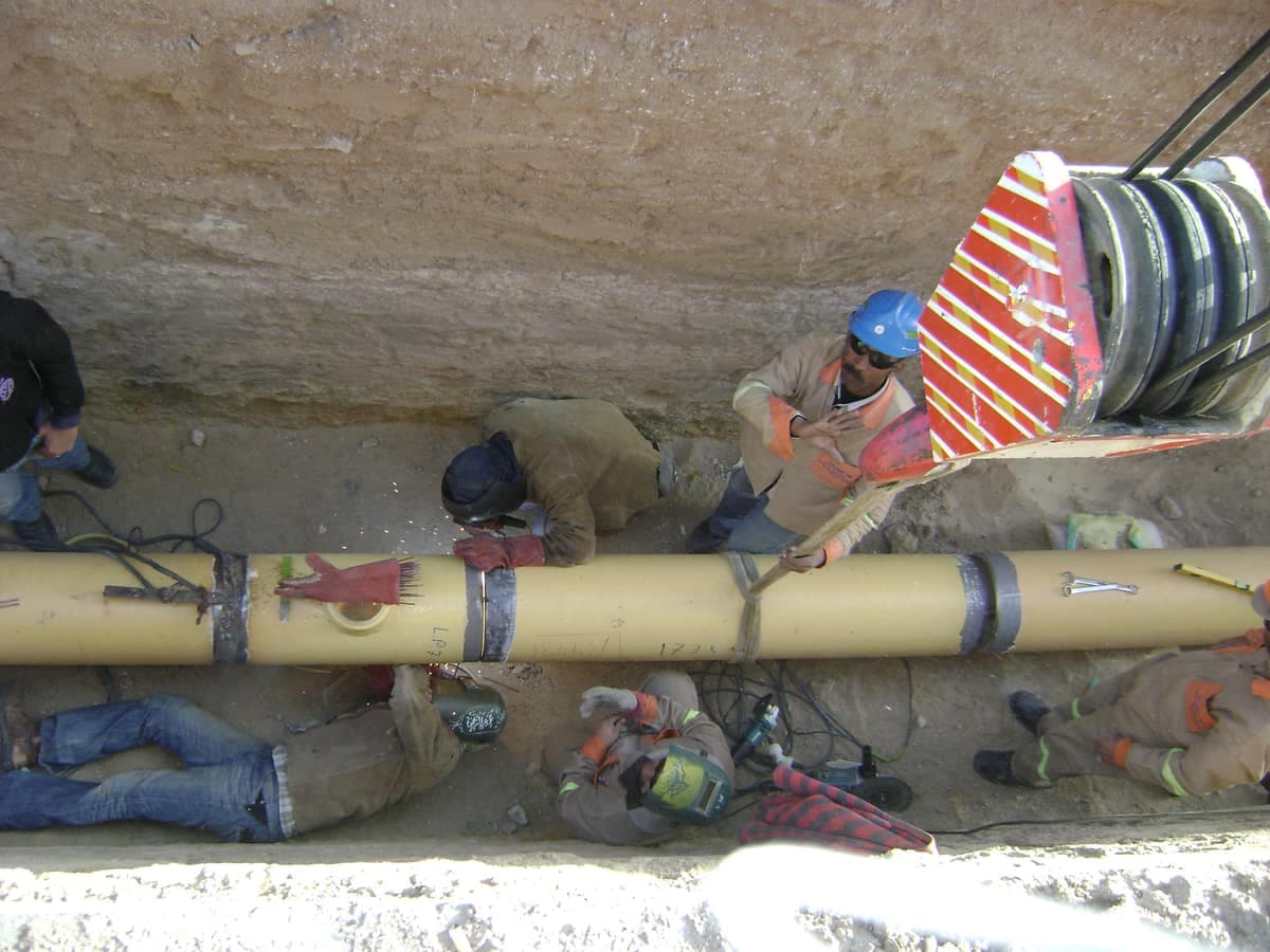 Workers laying a coated hydrant main into an open trench at Hurghada Airport