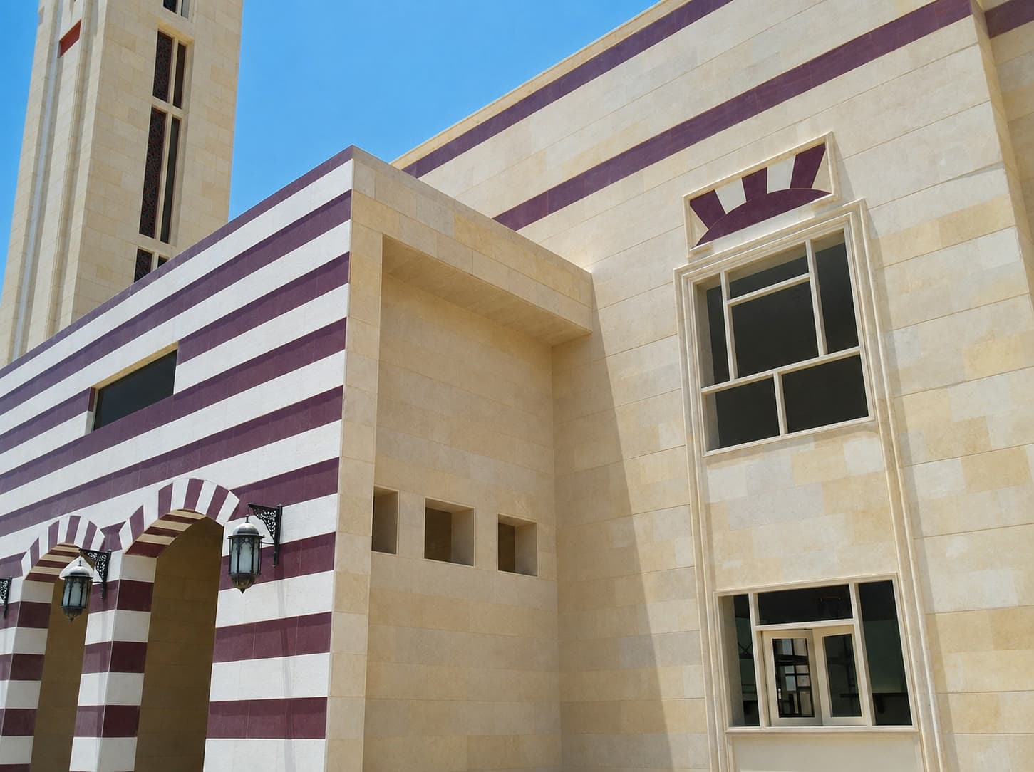 Masjid Aljazaya — stone facade with banded cladding and arched entrance