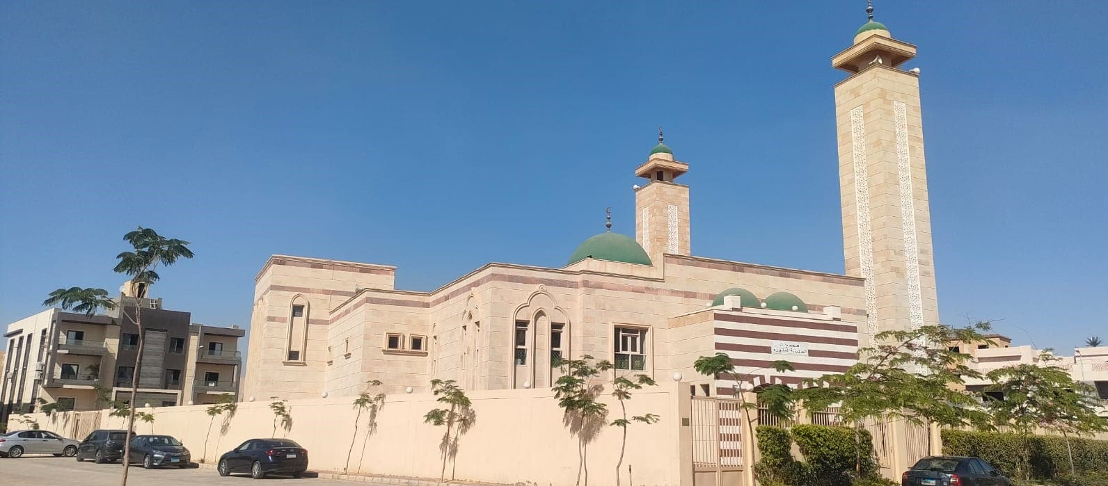 Masjed Almadina — the stone-clad mosque with green dome and minarets, seen from the street