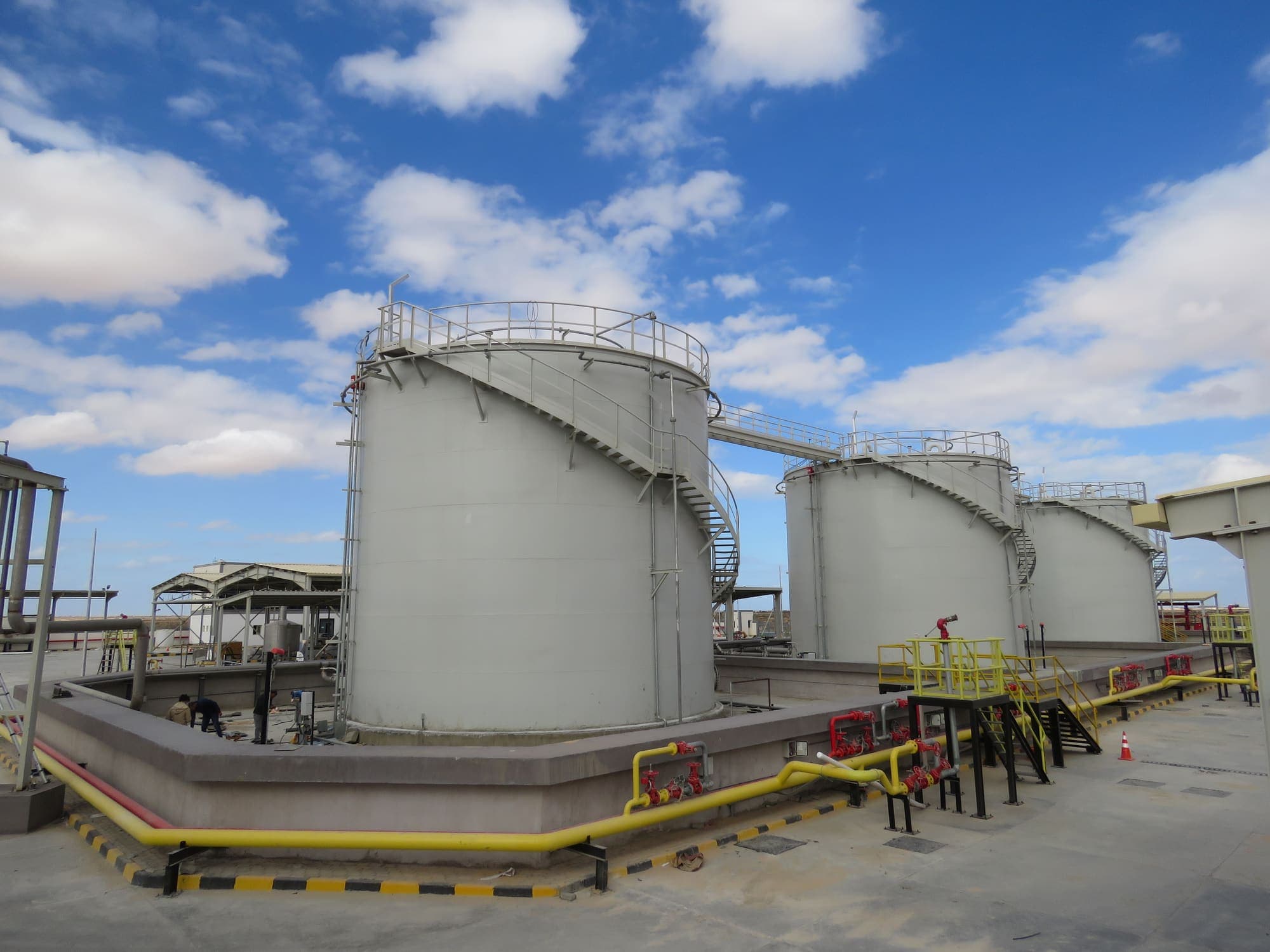 Al Majd · Warner Lewis fuel storage tanks in a concrete bund with firewater and product pipework under a blue sky