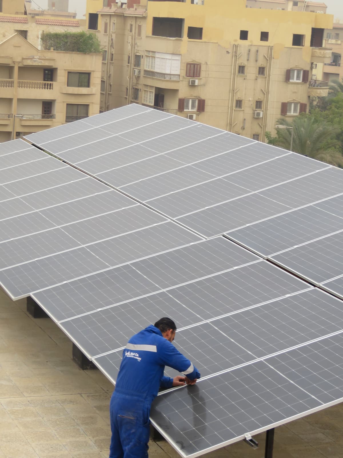 Al Majd technician installing rooftop PV modules at Al-Andalus International School