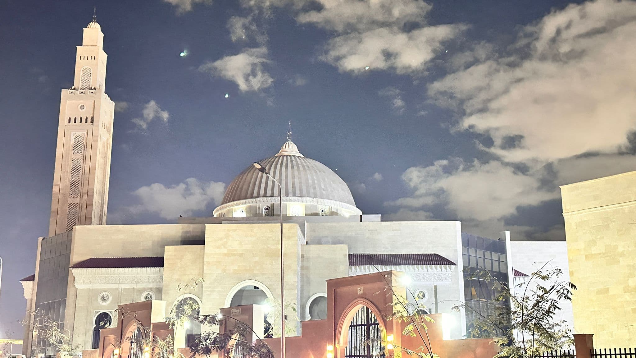 Masjid Al-Emam Al-Zahabi at night — dome and minaret lit against the sky